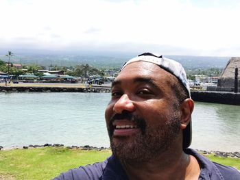 Portrait of smiling mid adult man in river against cityscape