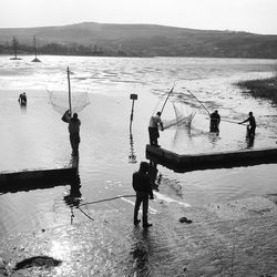 People fishing in sea against sky