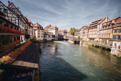 Canal amidst buildings in city against sky