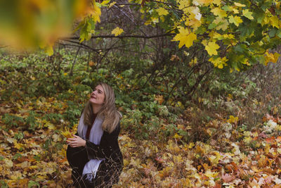 Young woman standing by plants during autumn