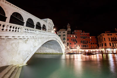 Arch bridge over river at night