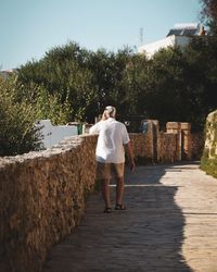 Rear view of man standing on walkway against sky