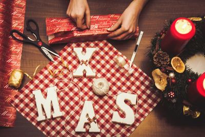 Cropped hands of woman wrapping christmas presents at table