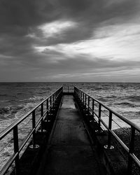 Pier on sea against cloudy sky