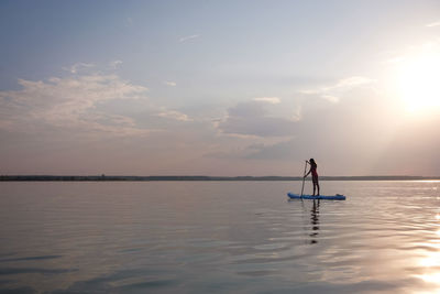 People on boat on lake against sky during sunset