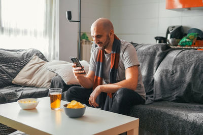 Young woman using phone while sitting at home