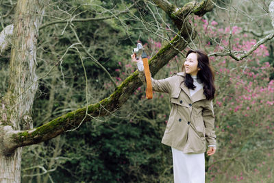 Full length of young woman standing in forest