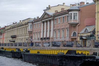 Buildings by river against sky in city