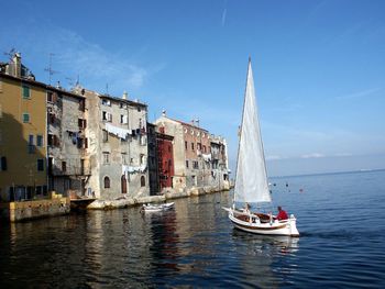 Boat sailing on sea by residential buildings