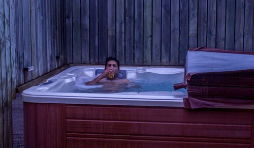 Portrait of man drinking while relaxing in hot tub 