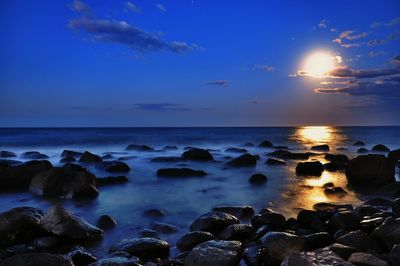 Scenic view of sea against moon and blue sky at dusk