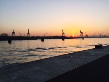 Silhouette pier on harbor against sky during sunset