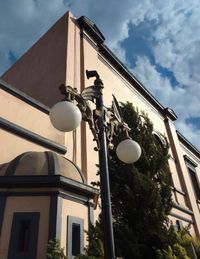 Low angle view of street light by building against sky