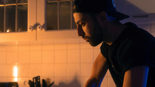 Side view of man standing in kitchen