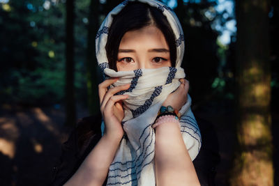 Close-up of young woman with eyes closed against trees