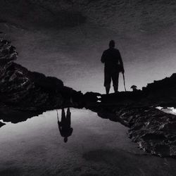 Silhouette man on lake against sky