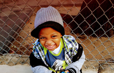 Portrait of a cute young boy smiling at school gate.