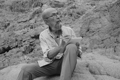 Portrait of young man sitting on rock