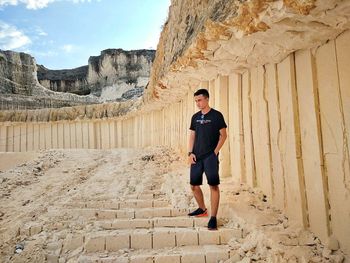 Full length of man standing on rock against sky