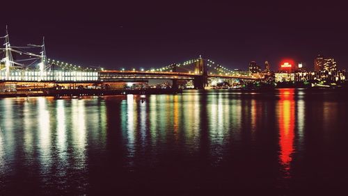 Illuminated bridge over river at night