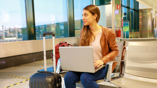 Young woman using phone while sitting on seat