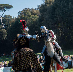 Men wearing armor costumes riding horses on field
