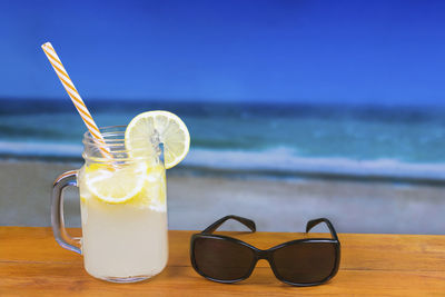 Close-up of drink on table at beach against sky