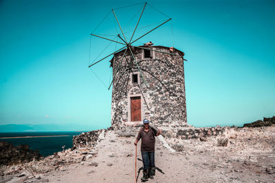 Rear view of traditional windmill by sea against sky