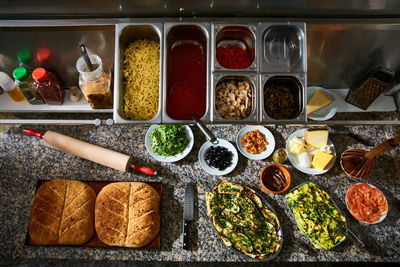 Top view of baking tray with hot freshly baked focaccia bread on marble table with various ingredients in restaurant kitchen