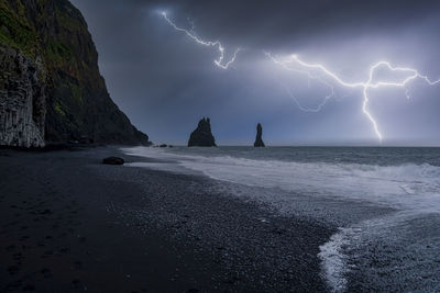 Idyllic view of lightning at black reynisfjara beach against stormy night