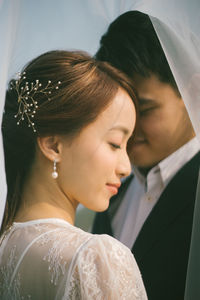 Close-up of romantic newlywed couple under veil