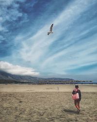 Full length of man flying over beach against sky