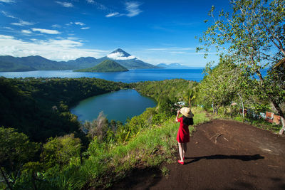 Woman standing by lake against sky