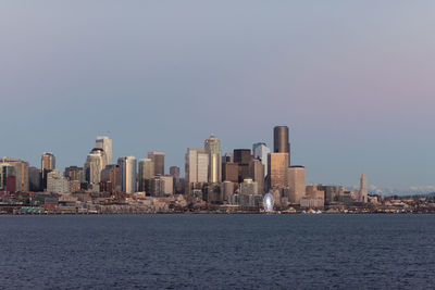 Sea by cityscape against clear sky