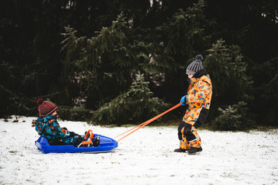 Rear view of people in boat against trees during winter