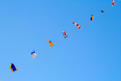 Low angle view of colorful flags against clear blue sky