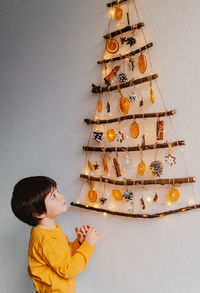 Little child looking at handmade craft christmas tree made from sticks and natural materials 