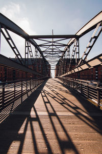 Metallic footbridge against sky during sunny day