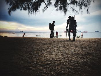 Rear view of people at beach against sky