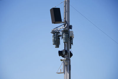 Low angle view of telephone pole against clear blue sky
