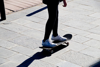 Low section of man skateboarding on footpath