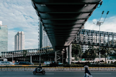 People on bridge against cloudy sky