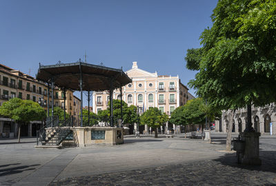 Street amidst buildings against clear blue sky