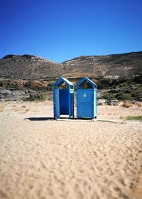 Lifeguard hut on beach against clear blue sky