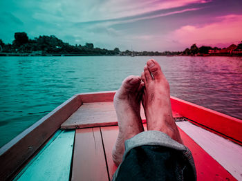 Low section of man on boat in lake against sky