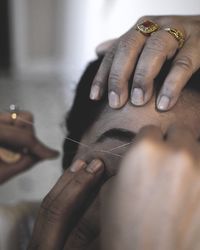 Cropped image of beautician hand threading eyebrows of woman
