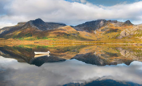 Wonderful mountainous landscape in norway reflected on the water surface with a small rowboat