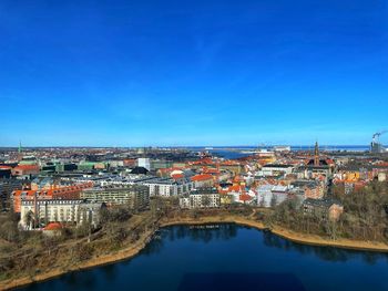 High angle view of townscape by river against clear blue sky