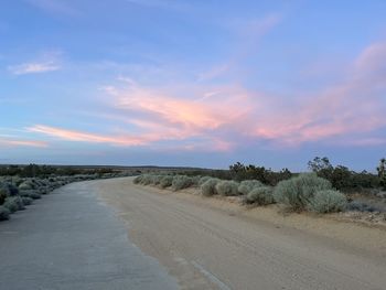 Road amidst field against sky