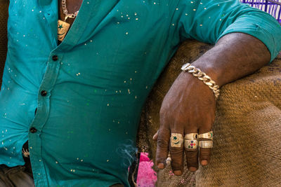 Midsection of man wearing golden jewelries